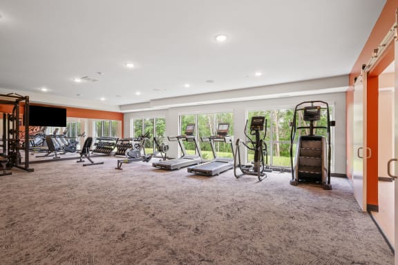 a gym with exercise equipment on the floor and large windows