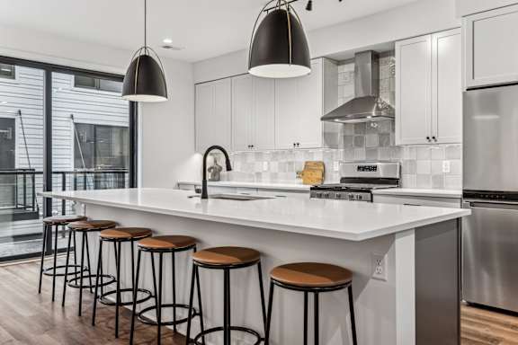 A modern kitchen with white countertops and stainless steel appliances.