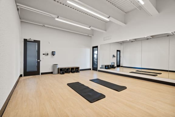 a yoga room with four yoga mats on the floor and a mirrored wall
