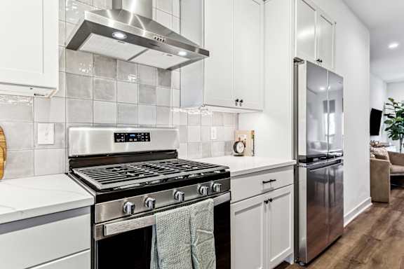A modern kitchen with a stainless steel oven and white cabinets.