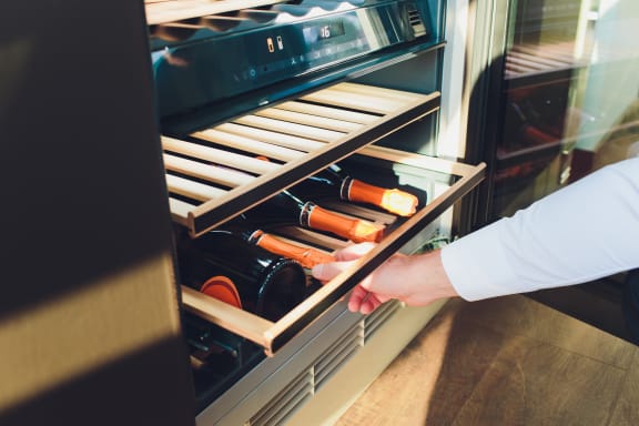 a man is taking a bottle of wine out of a refrigerator