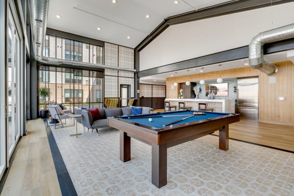 a common room with a pool table and lounge area