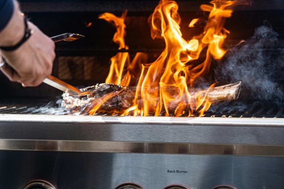 a person is cooking on a grill with fire