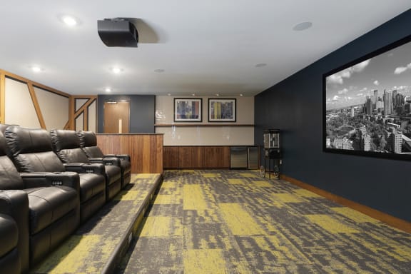 a living room with a large screen tv and leather couches