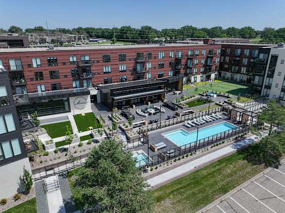 An aerial view of a large apartment complex with a swimming pool and a clock on the building.