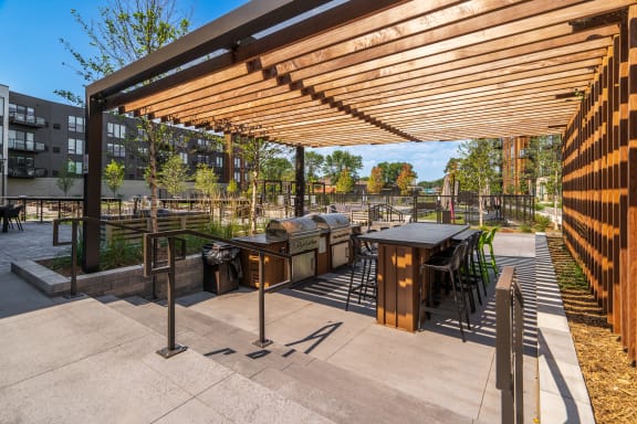 an outdoor patio with a barbecue grill and tables and chairs