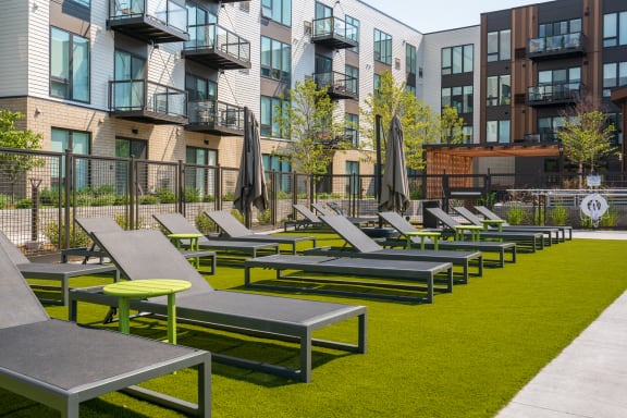 an outdoor lounge area with lounge chairs and umbrellas on a sunny day