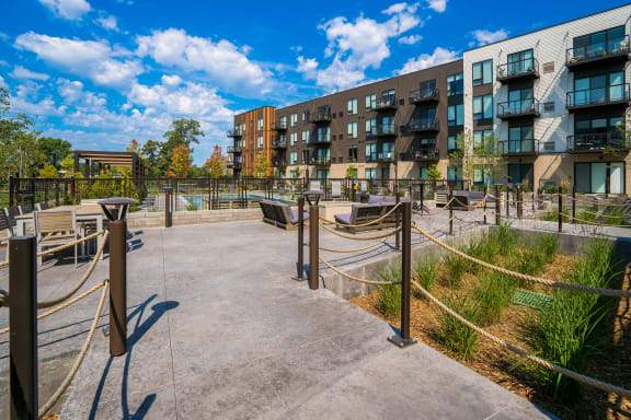 an open area with benches and rope barriers in front of an apartment building