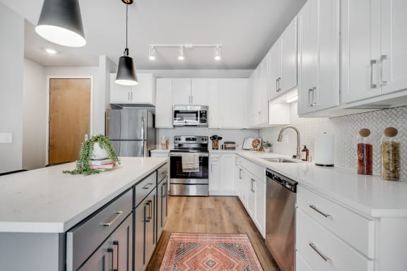 a kitchen with white cabinets and a rug on the floor