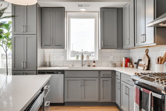 a kitchen with gray cabinets and white countertops