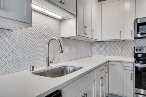a kitchen with white cabinets and a stainless steel sink
