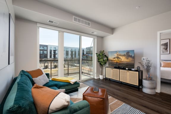 a living room with a green couch and a large window with a view of a building
