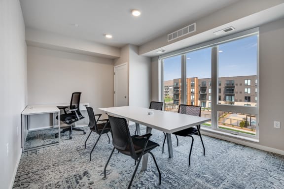 a meeting room with a large window and a table and chairs