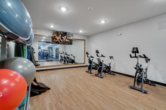 a spacious fitness room with hardwood flooring and a large mirror with a reflection of a