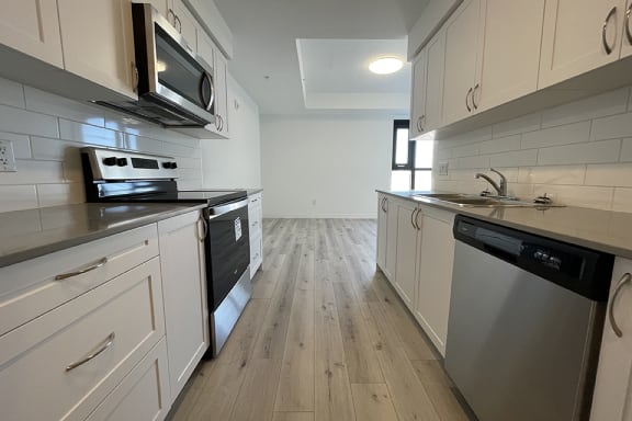Bayfield Tower 1 bedroom 1 bathroom variation A walk-through galley kitchen with stainless steel appliances as seen from the entry area