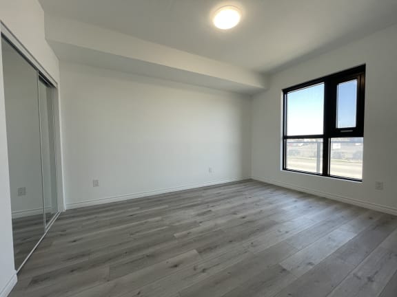 Bayfield Tower Apartments 1 bedroom 1 bathroom variation C bedroom with sliding mirror closet door and large window