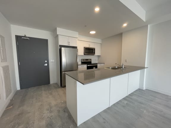 Bayfield Tower Apartments 1 bedroom 1 bathroom variation D kitchen with large breakfast bar, stainless steel appliances and white cabinets