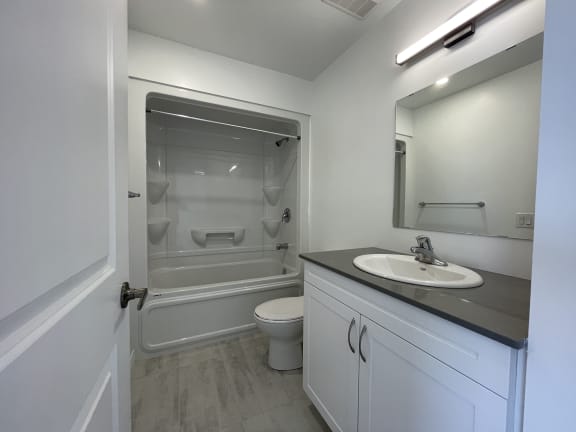 Bayfield Tower Apartments 2 bedroom 1 bathroom variation A bathroom with vanity, large mirror, toilet and tub with a shower