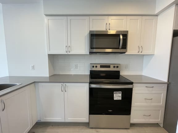 Bayfield Tower Apartments 2 bedroom 1 bathroom variation B kithcen with stainless steel stove, over-the-range microwave and white cabinets