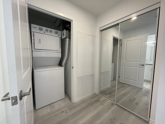 Bayfield Tower Apartments 2 bedroom 2 bathroom variation A stacked washer and dryer next to a closet with double sliding mirror doors