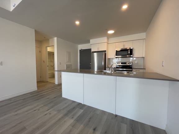 Bayfield Tower 2 bedroom 2 bathroom variation B open-concept kitchen with breakfast bar, stainless steel appliances and white cabinets