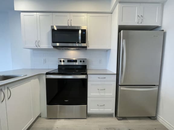 Bayfield Tower Apartments 3 bedroom 2 bathroom variation A kitchen with stainless steel appliances, quartz countertops and white cabinets