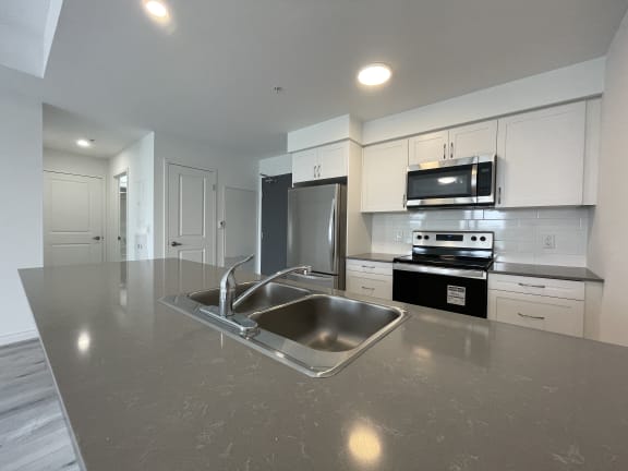 Bayfield Tower 2 bedroom 2 bathroom variation E kitchen with breakfast bar with quartz countertops, double kitchen sink, stainless steel appliance and white cabinets