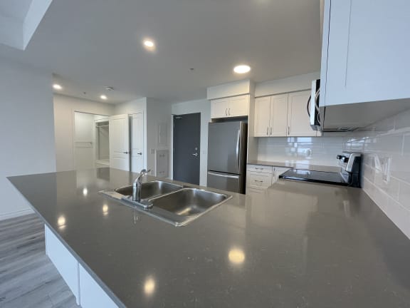 Bayfield Tower Apartments 3 bedroom 2 bathroom variation B kitchen with breakfast bar, quartz countertops and stainless steel appliances