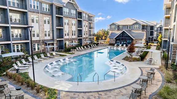 A large, modern residential complex with a swimming pool and landscaped gardens.