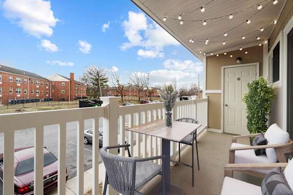 A patio with a table and chairs overlooking a parking lot.