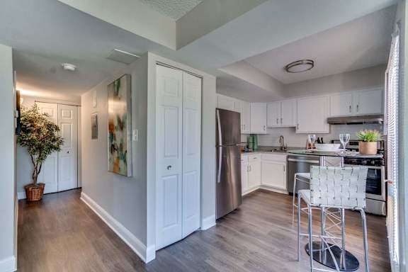 A modern kitchen with white cabinets and a stainless steel refrigerator.