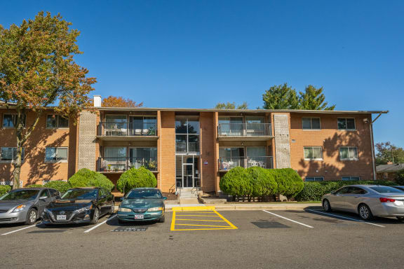 A parking lot in front of a building with cars parked.