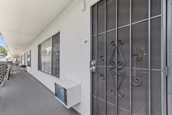A white building with a glass door and a number 211 on the wall.