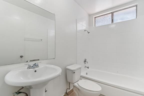 A white bathroom with a sink, toilet and bathtub.