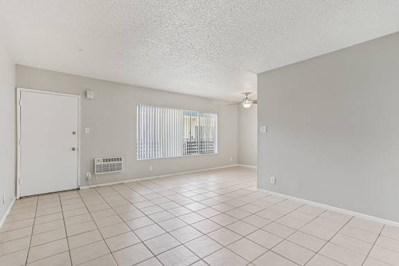 A spacious room with a white door and a window with blinds.