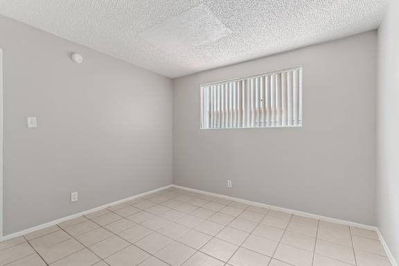 A room with a window covered by white blinds.