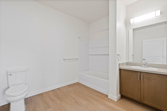 A white bathroom with wooden floors and white walls.