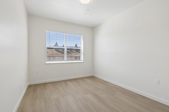 A room with a window showing a view of a hill with trees.