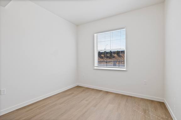 A room with a window and wooden flooring.