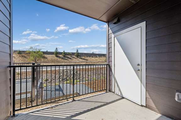A patio with a white door and a black railing.