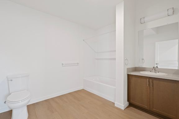 A white toilet is in a small room with a sink and a bathtub.