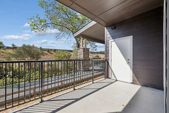 A balcony with a white door and a black railing.