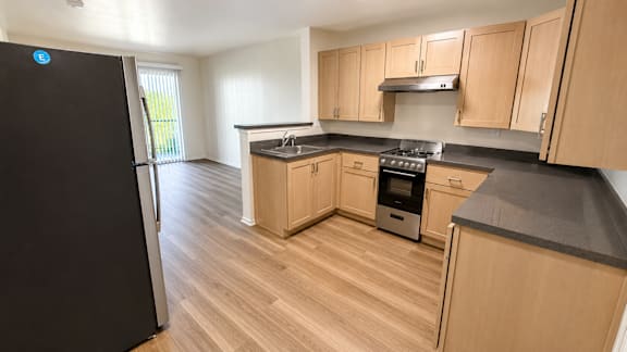 A kitchen with wooden cabinets and a black fridge.