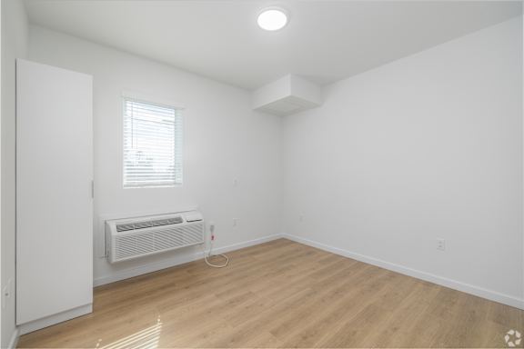 A room with a window and a wall-mounted air conditioner.
