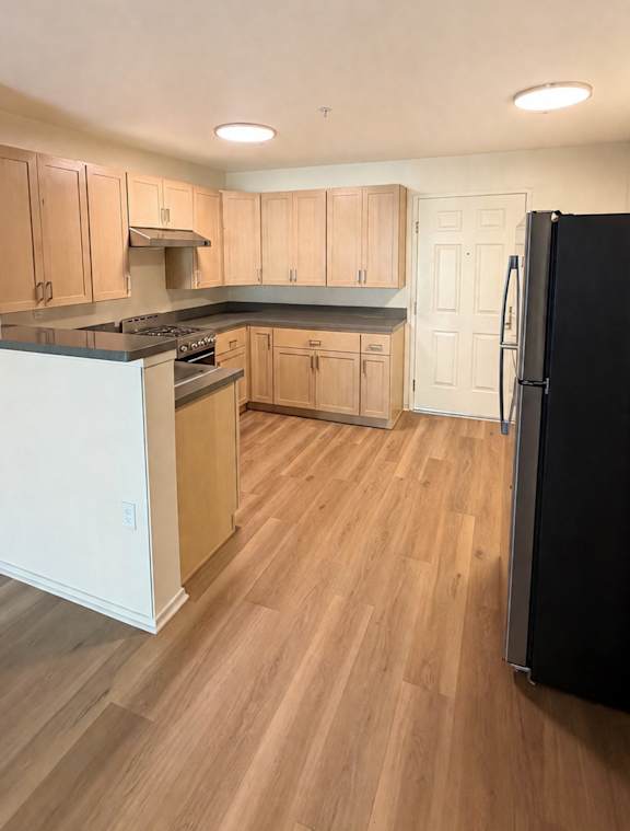 A kitchen with wooden floors and white appliances.