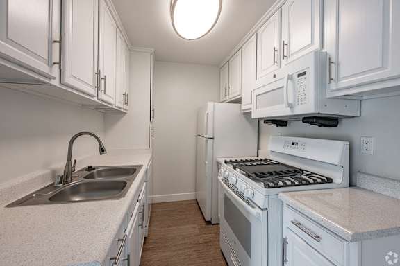 A white kitchen with a sink, stove, and refrigerator at Oak Park Apartments, Monrovia, 91016
