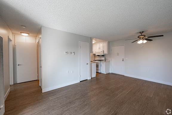 A room with a ceiling fan and a kitchenette in the background at Oak Park Apartments, Monrovia, 91016