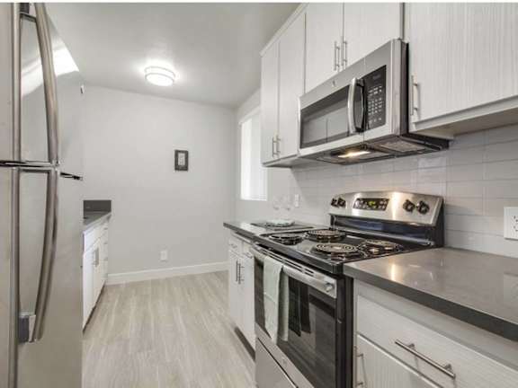 A kitchen with a stove top oven and a microwave above it.