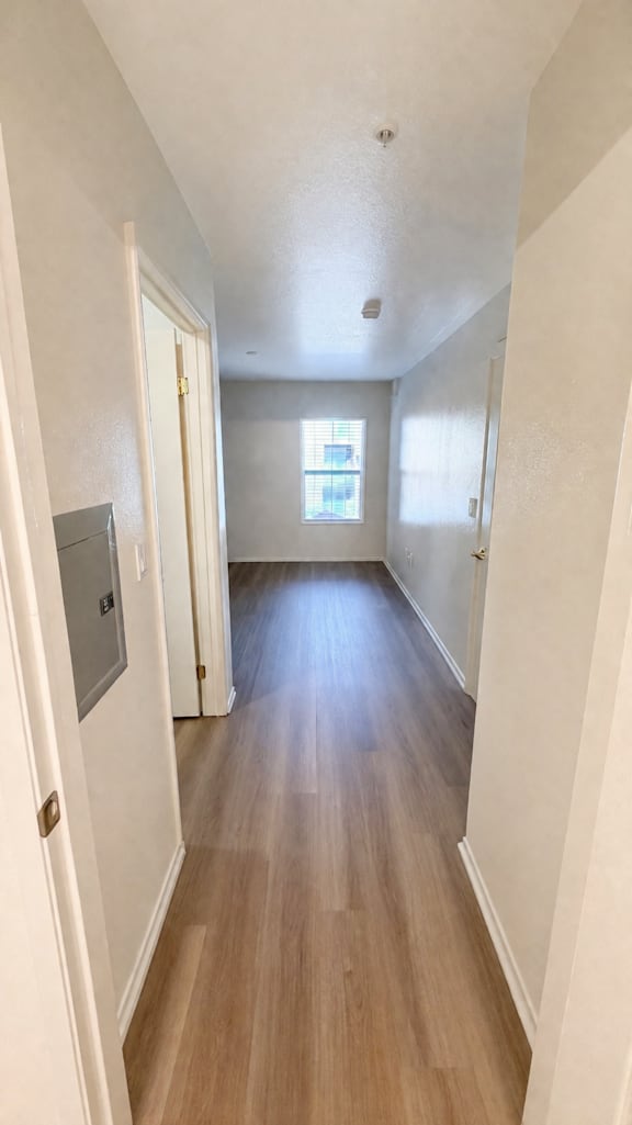 A long hallway with wood floors and white walls.