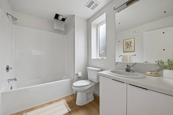 A white bathroom with a toilet, sink, and bathtub.